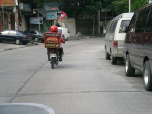 JULY 5 , 2008 , SAN JUAN CITY , PHILIPPINES - PIZZA HUT DELIVERY SERVICE CREW ON A MOTORCYCLE PASSING ON A ROAD