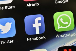 In this Thursday, Nov. 15, 2018 file photo the icons of Facebook and WhatsApp are pictured on an iPhone in Gelsenkirchen, Germany