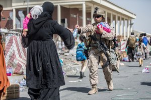 A Marine with Special Purpose Marine Air-Ground Task Force-Crisis Response-Central Command provides water to families during an evacuation at Hamid Karzai International Airport, Kabul, Afghanistan, Aug. 22. U.S. service members are assisting the Department of State with an orderly drawdown of designated personnel in Afghanistan.