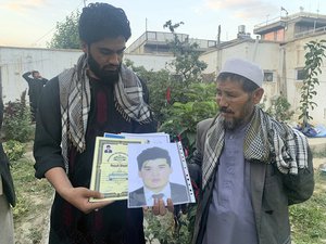 Mohammed Jan Sultani's father, Ali, right, looks at his son's Taekwondo championship certificates along with picture of him during an interview with The Associated Press in Kabul, Afghanistan, Sunday, Aug. 29, 2021