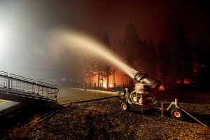 Seen in a long camera exposure, a snowmaking machine blasts water as the Caldor Fire burns at Sierra-at-Tahoe ski resort on Monday, Aug. 30, 2021, in Eldorado National Forest