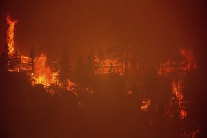 Seen from South Lake Tahoe, Calif., flames from the Caldor Fire consume three homes on Monday, Aug. 30, 2021.