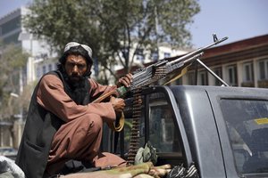 Taliban fighter sit on the back of vehicle with PK machine gun in front of main gate leading to Afghan presidential palace, in Kabul, Afghanistan, Monday, Aug. 16, 2021.