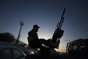 A Libyan army soldier stands guard sitting on an antiaircraft truck during the handover of the Nawaseen military compound, which was the headquarters of Libyan militias, in Souk al-Juma district, Tripoli, Libya, Thursday, Nov. 21, 2013.