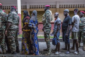 Civilians and soldiers line up to vote at the Boulbinet Deaf School in Conakry, Guinea, Sunday Oct. 18, 2020