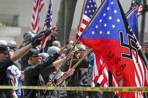 File - A white supremacist group salutes American flags and banners with swastikas at Los Angeles City Hall on Saturday, April 17,2010.