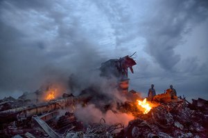 In this Thursday, July 17, 2014 file photo, people walk among the debris at the crash site of Malaysia Airlines Flight 17 passenger plane near the village of Grabove, Ukraine.