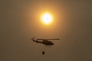 A helicopter flies over a wildfire in Estepona, Spain, Thursday, Sept. 9, 2021.