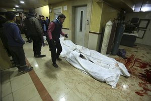 Relatives stand around bodies of people killed in airstrikes in the city of Idlib, Syria, Wednesday, Jan. 15, 2020.