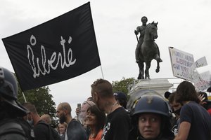 Protesters march with a banner reading "Freedom" during a demonstration against the health pass, Saturday, Aug. 21, 2021 in Paris. People denounce a COVID-19 health pass needed to access restaurant, long-distance trains and other venues