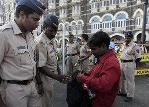 File - Indian police officers check a bag of a man outside the Taj Mahal hotel in Mumbai, India, Friday, Dec. 24, 2010.