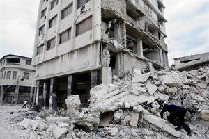 Members of a Colombian rescue team check a collapsed building after speaking with a woman who claims she received a text message from her husband two days ago. Port au Prince Haiti was rocked by a massive earthquake, Tuesday January 12, devastating the city and leaving thousands dead. Photo Marco Dormino