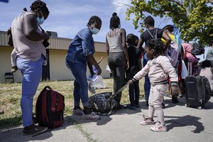 Haitian migrant Rabbiatu Yunusah, 34, second from left, looks on as her daughter Leila, 3, pulls on her backpack while waiting in line to board a bus at a humanitarian center after they were released from United States Border Patrol upon crossing the Rio Grande and turning themselves in seeking asylum, Wednesday, Sept. 22, 2021, in Del Rio, Texas