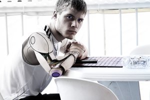 Man with steel artificial arm sitting in front of white table