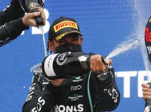 Mercedes' Lewis Hamilton, center, celebrates on the podium after winning the race