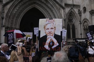 File - A supporter of WikiLeaks founder Julian Assange holds a placard after the first hearing in the Julian Assange extradition appeal, at the High Court in London, Wednesday, Aug. 11, 2021.