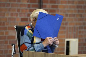 The accused Josef S. covers his face as he sits at the court room in Brandenburg, Germany, Thursday, Oct. 7, 2021