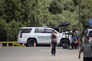 Reporters and curious onlookers walk along a road lead to the entrance of the Carlton Reserve during a search for Brian Laundrie, Tuesday, Sept. 21, 2021, in Venice, Fla.