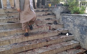 A man walks down blood-stained steps of a mosque following a bombing in Kunduz province, northern Afghanistan, Friday, Oct. 8, 2021. A powerful explosion in a mosque frequented by a Muslim religious minority in northern Afghanistan on Friday has left dozens dead.