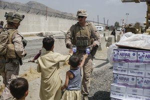 KABUL, Afghanistan (Aug. 20, 2021) A U.S. Navy corpsman with Special Purpose Marine Air-Ground Task Force - Crisis Response - Central Command, hands out water to children during an evacuation at Hamid Karzai International Airport, Kabul, Afghanistan, Aug. 20.