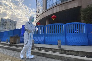 A worker in protectively overalls and disinfecting equipment walks outside the Wuhan Central Hospital where Li Wenliang, the whistleblower doctor who sounded the alarm and was reprimanded by local police for it in the early days of Wuhan's pandemic, worked in Wuhan in central China's Hubei province on Saturday, Feb. 6, 2021.