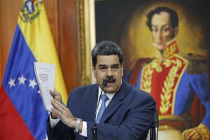 Venezuelan President Nicolas Maduro holds up a copy of his country's case taken to the International Criminal Court regarding U.S. sanctions during a press conference at Miraflores presidential palace in Caracas, Venezuela, Friday, Feb. 14, 2020