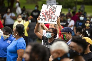 In this May 16, 2020, file photo, a woman holds a sign during a rally to protest the shooting of Ahmaud Arbery, in Brunswick, Georgia. Jury selection in the case is scheduled to begin Monday, Oct. 18.