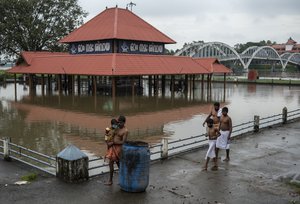 Hindu devotees walk back after performing rituals, past an inundated Shiva temple on the banks of the Periyar River following heavy rains in Kochi, Kerala state, India, Tuesday, Oct. 12, 2021. Dozens have been killed and many are missing in Kerala following torrential rain.