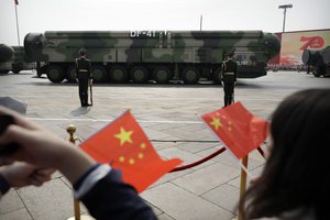 In this Oct. 1, 2019, file photo spectators wave Chinese flags as military vehicles carrying DF-41 ballistic missiles roll during a parade to commemorate the 70th anniversary of the founding of Communist China in Beijing