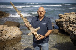 Jacob Sharvit, director of the Marine Archaeology Unit of the Israel Antiquities Authority holds a meter-long (yard-long) sword, that experts say dates back to the Crusaders is on display in Mediterranean seaport of Cesarea, Israel, Tuesday, Oct. 19, 2021