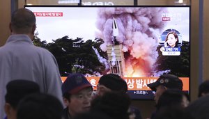 People watch a TV showing a file image of an unspecified North Korea's missile launch during a news program