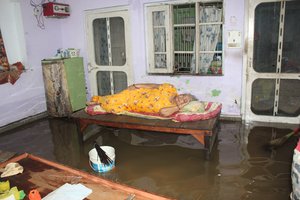 A woman takes a rest in her flooded house after a heavy rain in Jammu, India, 26 August 2020.