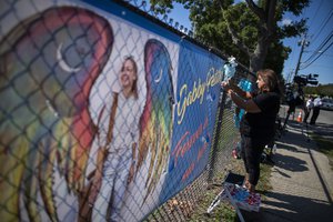 A woman places a decoration near a poster after attending the funeral home viewing of Gabby Petito at Moloney's Funeral Home in Holbrook, N.Y. Sunday, Sept. 26, 2021