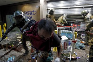 Police arrest a person suspected of stealing goods from a supermarket on the two-year anniversary of the start of anti-government mass protests over inequality, in Santiago, Chile, Monday, Oct. 18, 2021.