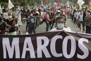 A protester wearing a protective mask holds a slogan during a rally to mark the 48th anniversary of the declaration of martial law on Monday, Sept. 21, 2020 in Quezon city, Philippines