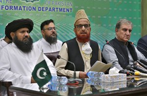 Pakistan's Foreign Minister Shah Mahmood Qureshi, right, and top religious leader Mufti Muneebur Rehman, center, who helped negotiate an end to a protest march by Islamists, give a press conference, in Islamabad, Pakistan, Sunday, Oct. 31, 2021.