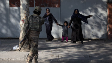 A Taliban soldier sends people away after an explosion at the entrance of a military hospital in Kabul.