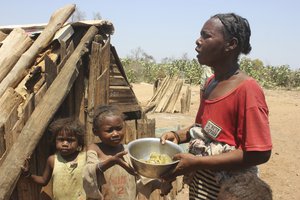 Toharano, mother of 18 children, with two of her children, holds a bowl in the village of Ankilimarovahatsy, Madagascar, Monday, Nov. 9, 2020