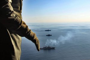 In this photo provided Saturday, Dec. 28, 2019, by the Iranian Army, warships sail in the Sea of Oman during the second day of joint Iran, Russia and China naval war games as a military crew stands in a helicopter.