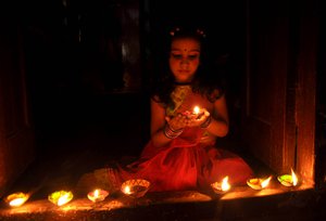 File - A girl lights a Diya or Earthen lamp ahead of the Diwali festival in Kolkata, India.