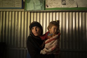 A woman waits with her child inside a doctor's office in Mirbacha Kot, Afghanistan on Monday, Oct. 25, 2021.