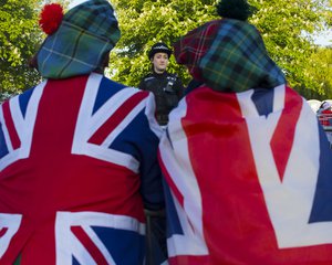 A police officer talks to spectators waiting alongside the route the royal couple will travel, prior to the wedding ceremony of Prince Harry and Meghan Markle at St. George's Chapel in Windsor Castle in Windsor, near London, England, Saturday, May 19, 2018.