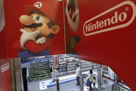 FILE - In this May 7, 2014, file photo, shoppers walk under the logo of Nintendo and Super Mario characters at an electronics store in Tokyo.