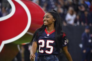 Olympic gymnast Simone Biles leads the Houston Texans onto the field before an NFL football game against the Tennessee Titans Sunday, Dec. 29, 2019, in Houston.