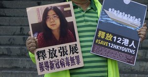 A pro-democracy activist holds placards with the picture of Chinese citizen journalist Zhang Zhan outside the Chinese central government's liaison office, in Hong Kong, Monday, Dec. 28, 2020. Zhang, a former lawyer and citizen journalist from Shanghai, has been sentenced to four years in prison for her reporting on the initial coronavirus outbreak in Wuhan, China. The activists demand the releases of Zhang, as well as the 12 Hong Kong activists detained at sea by Chinese authorities. (AP Photo/Kin Cheung)