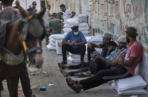 A Palestinian man loads a car with sacks of flour received from the UN Relief and Works Agency, (UNRWA), at a warehouse in Gaza City, Wednesday, Sept. 30, 2020