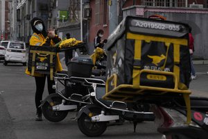 A delivery person for online food delivery platform Meituan prepares for work in Beijing, China, Sunday, Oct. 10, 2021.