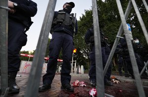 Polish police stand guard after activists threw paint symbolizing blood close to the parliament in Warsaw, Poland, Friday Oct. 8, 2021.