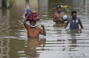 Sri Lankans wade through an inundated street following heavy rainfall at Malwana, on the outskirts of Colombo, Sri Lanka, Saturday, June 5, 2021.