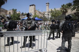 File - Israeli police officers stand guard as Palestinians pray during Friday prayers at a protest against construction access in being built on the Jewish side at the Ibrahimi Mosque, which Jews call the Tomb of the Patriarchs, in the West Bank city of Hebron, Friday, Aug. 13, 2021.